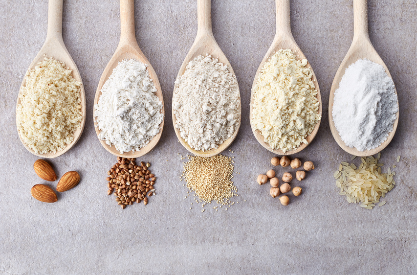 Wooden spoons of various gluten free flour (almond flour, amaranth seeds flour, buckwheat flour, rice flour, chick peas flour) from top view